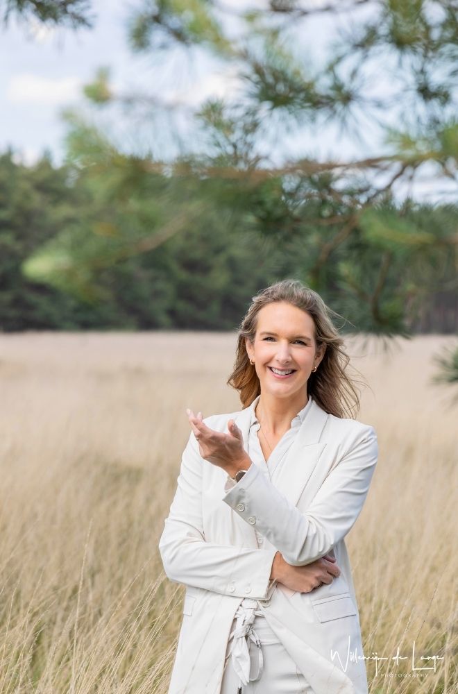 Vrouw reikt haar hand uit in de natuur, symbool voor loslaten en vertrouwen in je eigen pad.